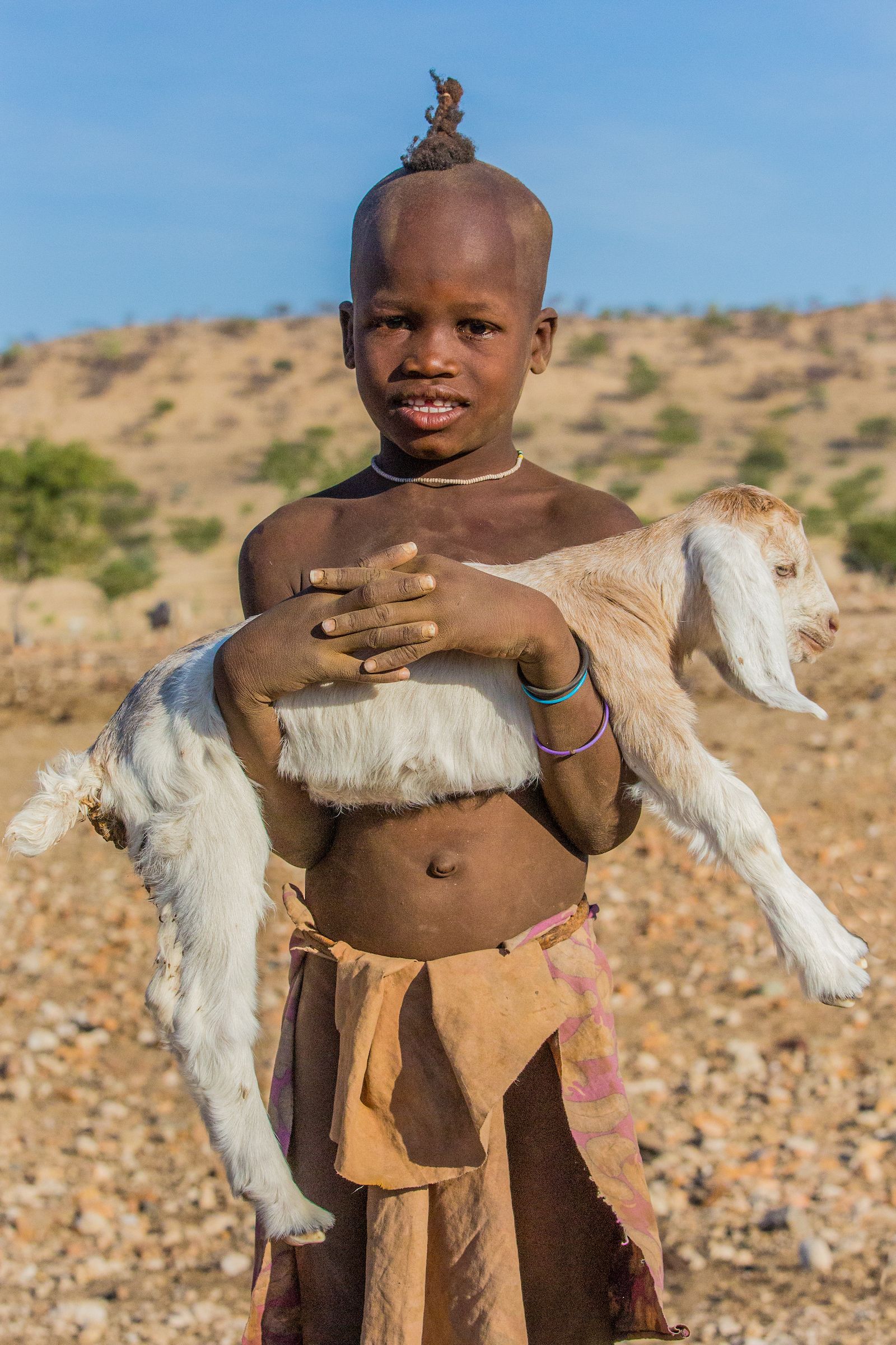 A young Himba boy and his goat on our photography tour in Namibia
