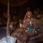 Himba woman and her child inside a hut