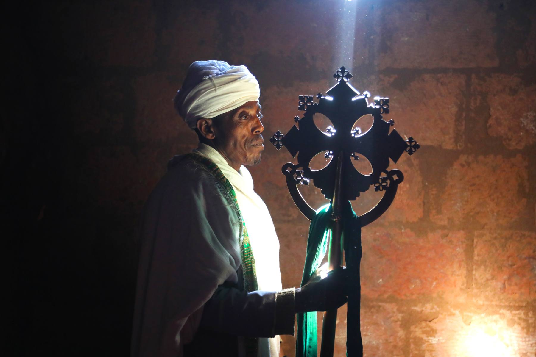 A ray of sunlight illuminates a priest's crucifix at Lalibela, Ethiopia