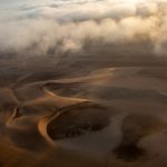 Sun shines through the encroaching fog over the Skeleton Coast in Namibia