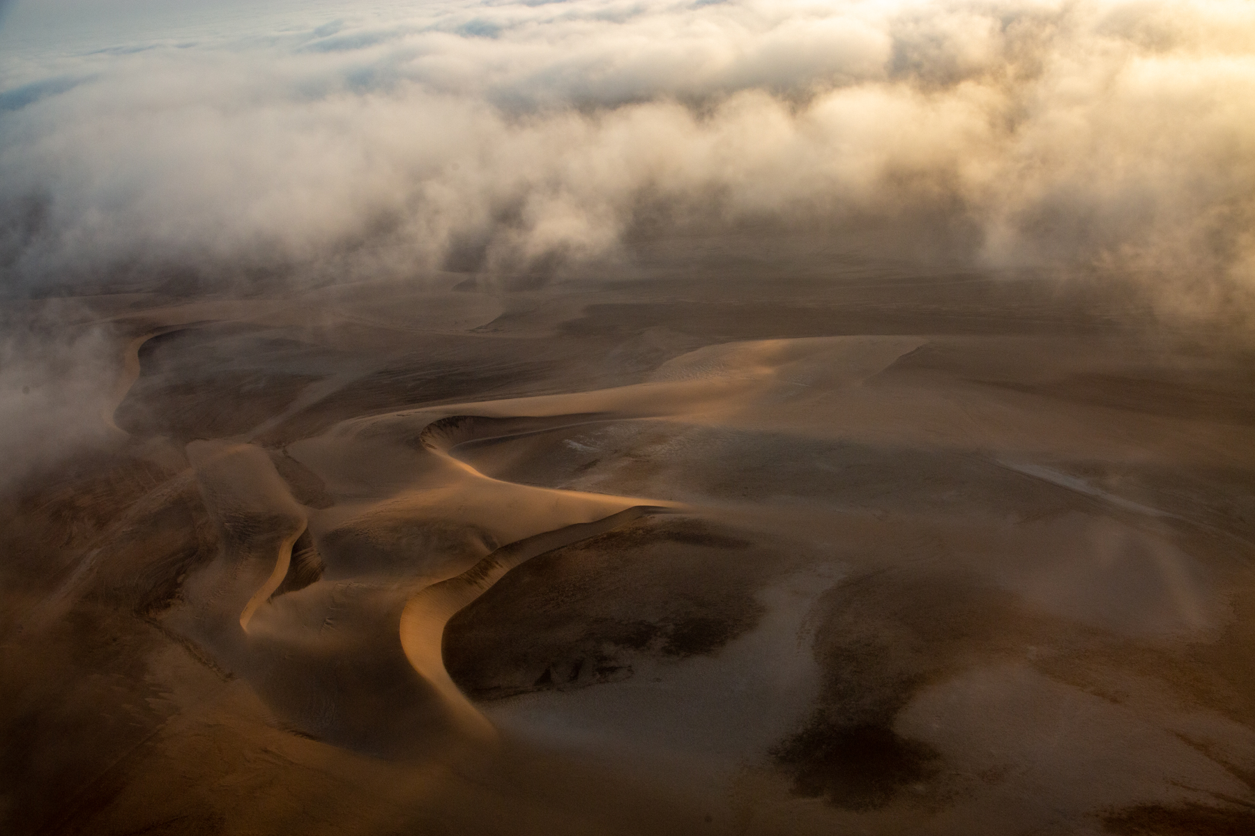 Sun shines through the encroaching fog over the Skeleton Coast in Namibia