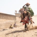 Lively and athletic Batonu horsemen ride their steeds in the streets of Parakou
