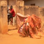 Egunguns frighten a young man who leaps into the entrance of his home to escape