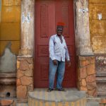 Man selling traditional Gobi hats in front of the mosque at Porto Novo. Gobis are worn by Beninese men to symbolise if they are married or single