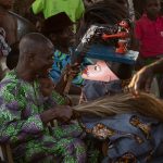A Guelede masked dancer is blessed by onlookers at a ceremony
