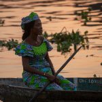 A Tofinu woman paddles her canoe to buy fresh water at sunset in Ganvie on our Benin photography tour
