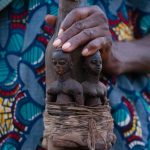 A Voodoo spirit bottle is held to give offerings to the Zangbeto divinity