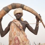 Portrait of Jeshep, a young Mundari man holding a 'Tung' musical instrument