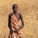 A simply dressed Larim girl works in the fields near her home