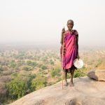 An elderly Lotuko woman stands high on the hill of the Ileu mountains on our South Sudan photo tour