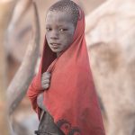 A young Mundari boy wanders through his cattle camp at sunrise