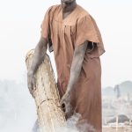 A Mundari drummer blesses the cowskin of his cylindrical drum on our photo tour of South Sudan