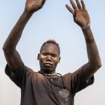 Mundari people will often hold their arms up to form the shape of their cows when you photograph them on a photo tour of South Sudan