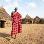 Portrait of Lokom, a Toposa man, standing in his village
