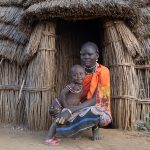 A Toposa woman and her young daughter in front of their hut in South Sudan