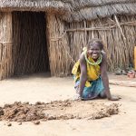 A Toposa woman takes a break from preparing mud and dung to line an Ekore granary