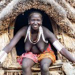 A Toposa woman sitting at the entrance to her Ekore, a stilted granary of her people