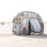 A Gabra woman outside her home in a sudden dust storm in the Chalbi