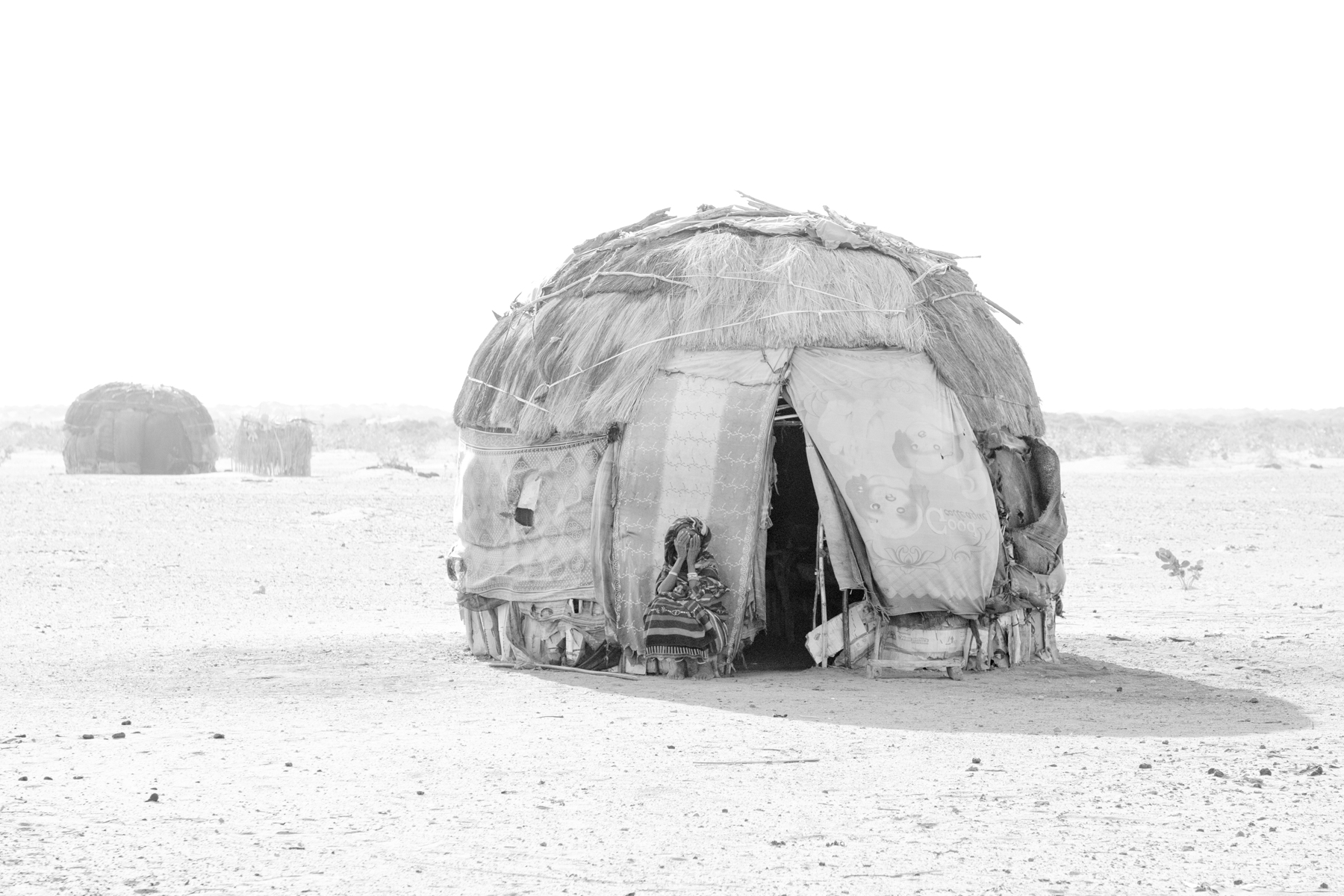 A Gabra woman shields her face from a sudden dust storm in the Chalbi