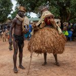 A guardian stands with the mask of Gambié in remote Ivory Coast