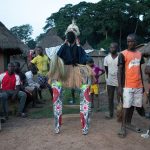 A stilt dancer takes a break between dances at Godufu