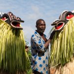 A guardian supervises the Goli Glan masked dancers of the Baoulé people