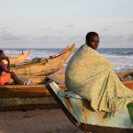 Young men contemplate a night at sea from their pirogues at Grand Bassam