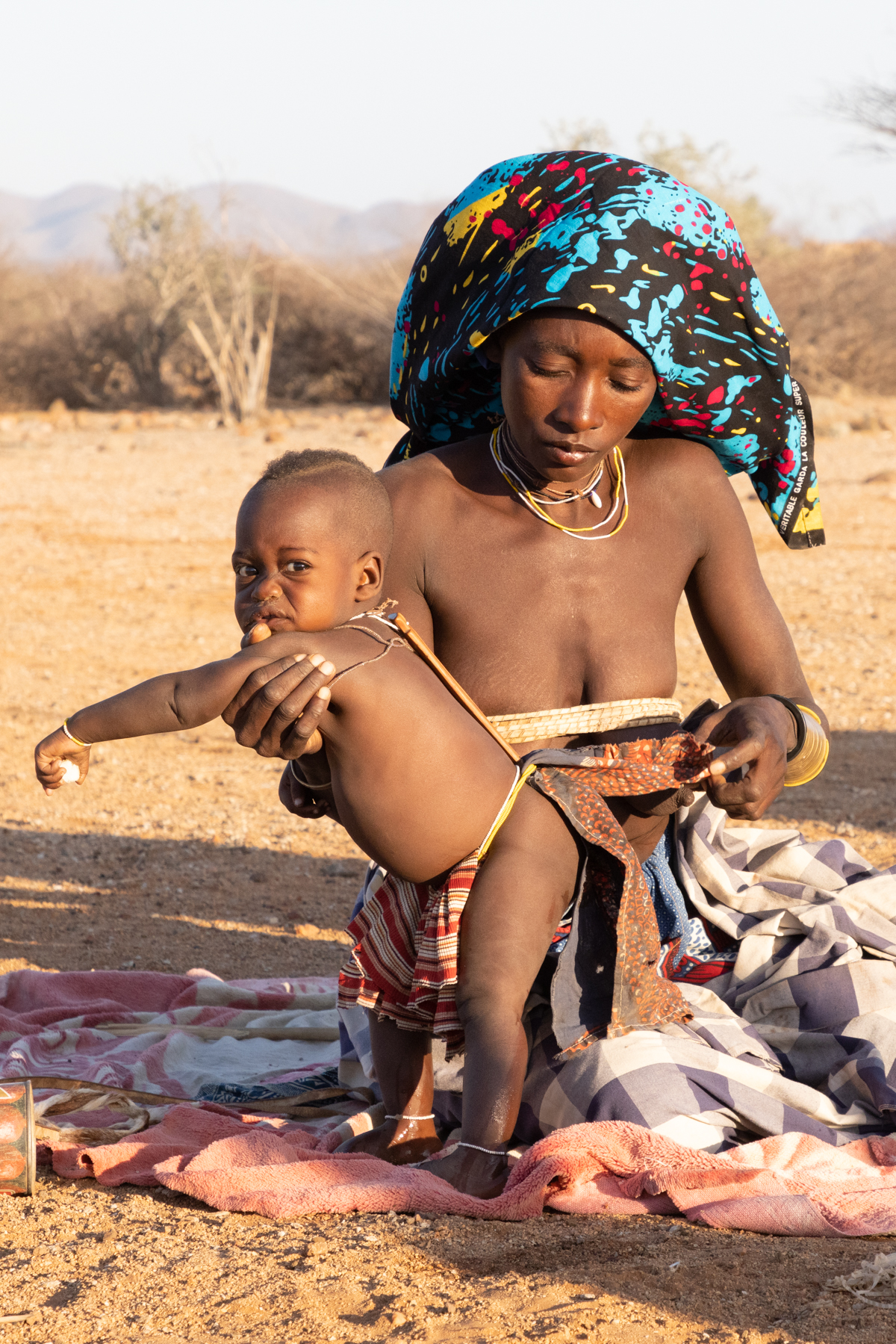A Ovakuvale mother fixes a traditional brace to her child in remote Angola