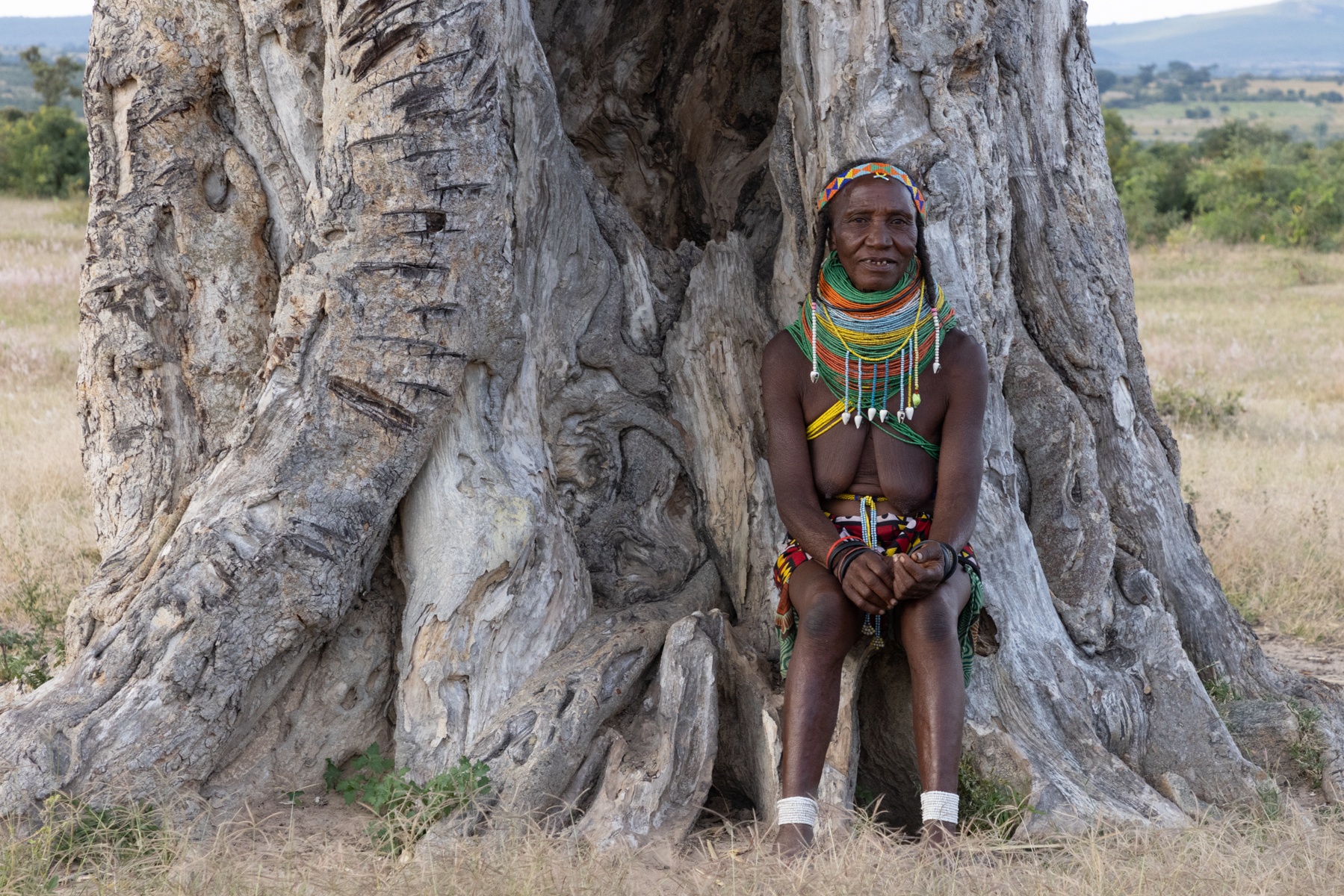 Portrait of an elderly Ovamwila woman sitting at the base of an ancient baobab in southern Angola