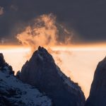 Small puffs of cloud appear as orange mist above the peaks next to the three iconic ‘Towers’ of the Paine Massif, Torres del Paine National Park (image by Virginia Wilde)
