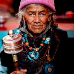 An elderly Ladakhi woman spins her mani wheel and chants Om Mani Padme Hum at Takmachik (image by Julie-Anne Davies)
