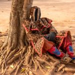 Dancing is tiring! An Egungun takes a break under a local fig tree in Benin (image by Inger Vandyke)