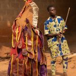An Egungun with his guardian in remote Benin (image by Inger Vandyke)