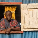 A resident of Ganvié watches as we cruise past his home in wooden pirogues (image by Inger Vandyke)