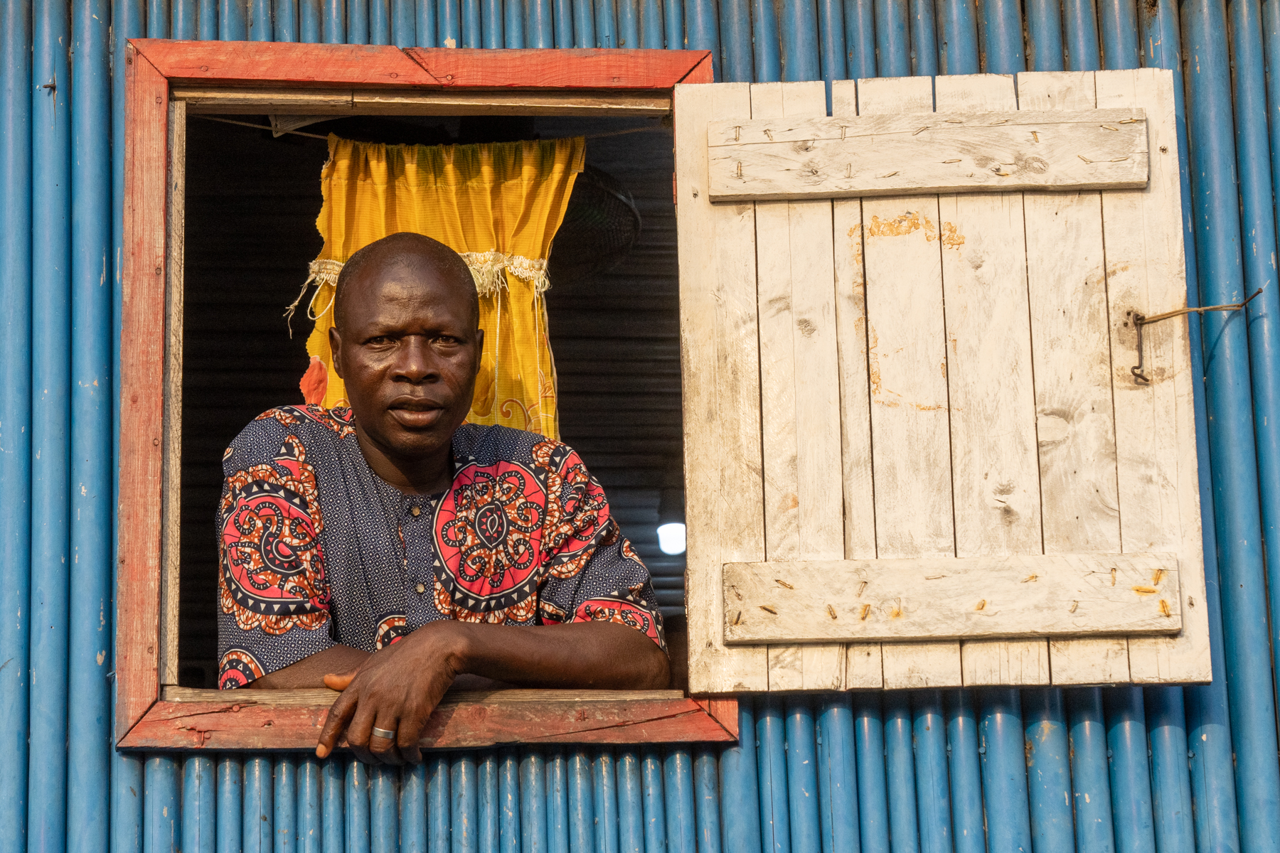 A resident of Ganvié watches as we cruise past his home in wooden pirogues (image by Inger Vandyke)