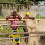 Young girls peer at us from lines of nets in a remote fishing village near the Nigerian border of Benin (image by Inger Vandyke)