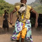 A Sakpata dancer enters the ceremony carrying a sacrificial chicken in his mouth! (image by Inger Vandyke)