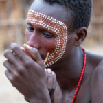 A young Arbore man paints his face to prepare for a wedding ceremony (image by Inger Vandyke)