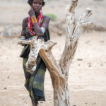 A beautiful Arbore woman resting against a dead tree trunk (image by Inger Vandyke)