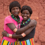 Benna best friends embrace and giggle in Alduba market (image by Inger Vandyke)