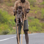 We all have to start somewhere! A father helps his Benna son to learn how to walk on stilts (image by Inger Vandyke)