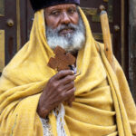 An elderly Christian priest holding his wooden crucifix outside the Cathedral of St George in Addis Ababa (image by Inger Vandyke)