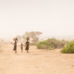 Dassanech women and child walking towards Omorate in a dust storm (image by Inger Vandyke)