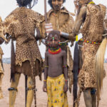 A young girl stands with Dassanech elders ahead of her initiation (image by Inger Vandyke)