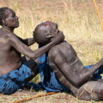 An elder renders an injured Donga stick fighter assistance in the field (image by Inger Vandyke)