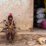 An elderly Hamer woman with her amusing dried flower, outside a local shop in Turmi (image by Inger Vandyke)