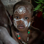 A young Karo child inside his home, surrounded by the family members who kindly invited us in for tea (image by Inger Vandyke)
