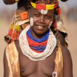 A smiling Karo woman has her hair done in an open-air salon. Karo women fashion their 'bobble' hair using ochre and animal fats (image by Inger Vandyke)