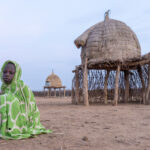 A young Nyangatom child wraps a blanket around him to stay warm at dawn (image by Inger Vandyke)