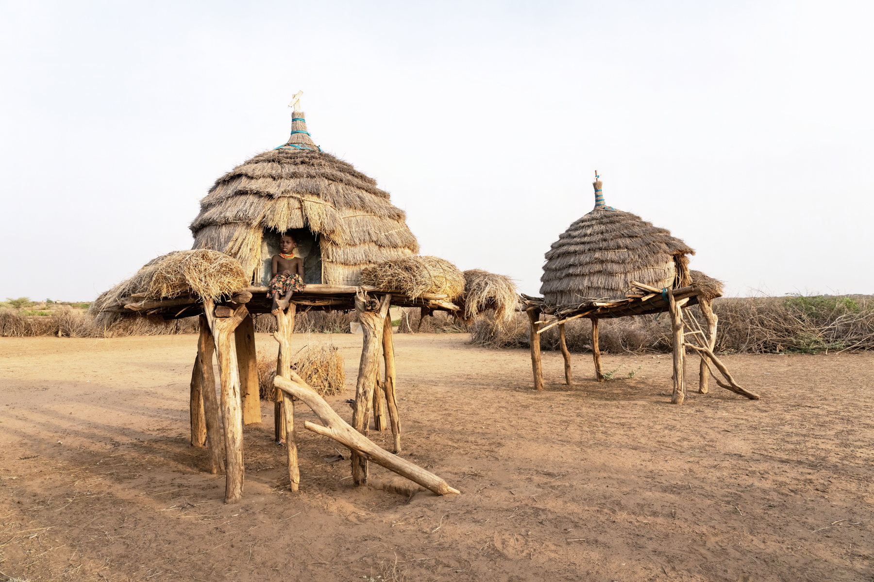 A young Nyangatom girl sitting in the hand sculpted granaries of her village (image by Inger Vandyke)